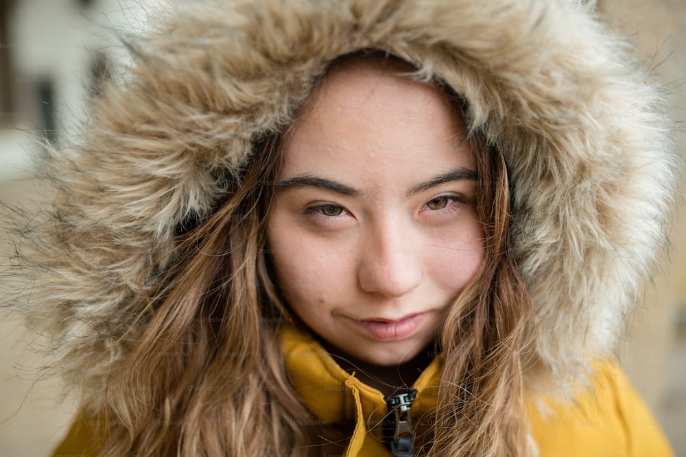 A close-up of young woman with Down syndrome weraing hood and looking at camera