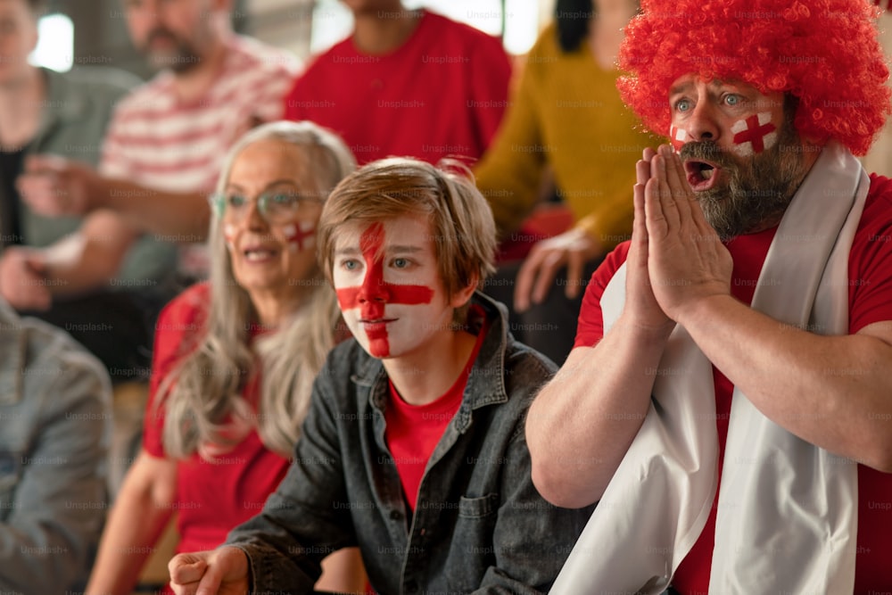 Tifosi di calcio entusiasti che sostengono una squadra nazionale inglese in una partita di calcio in diretta allo stadio.