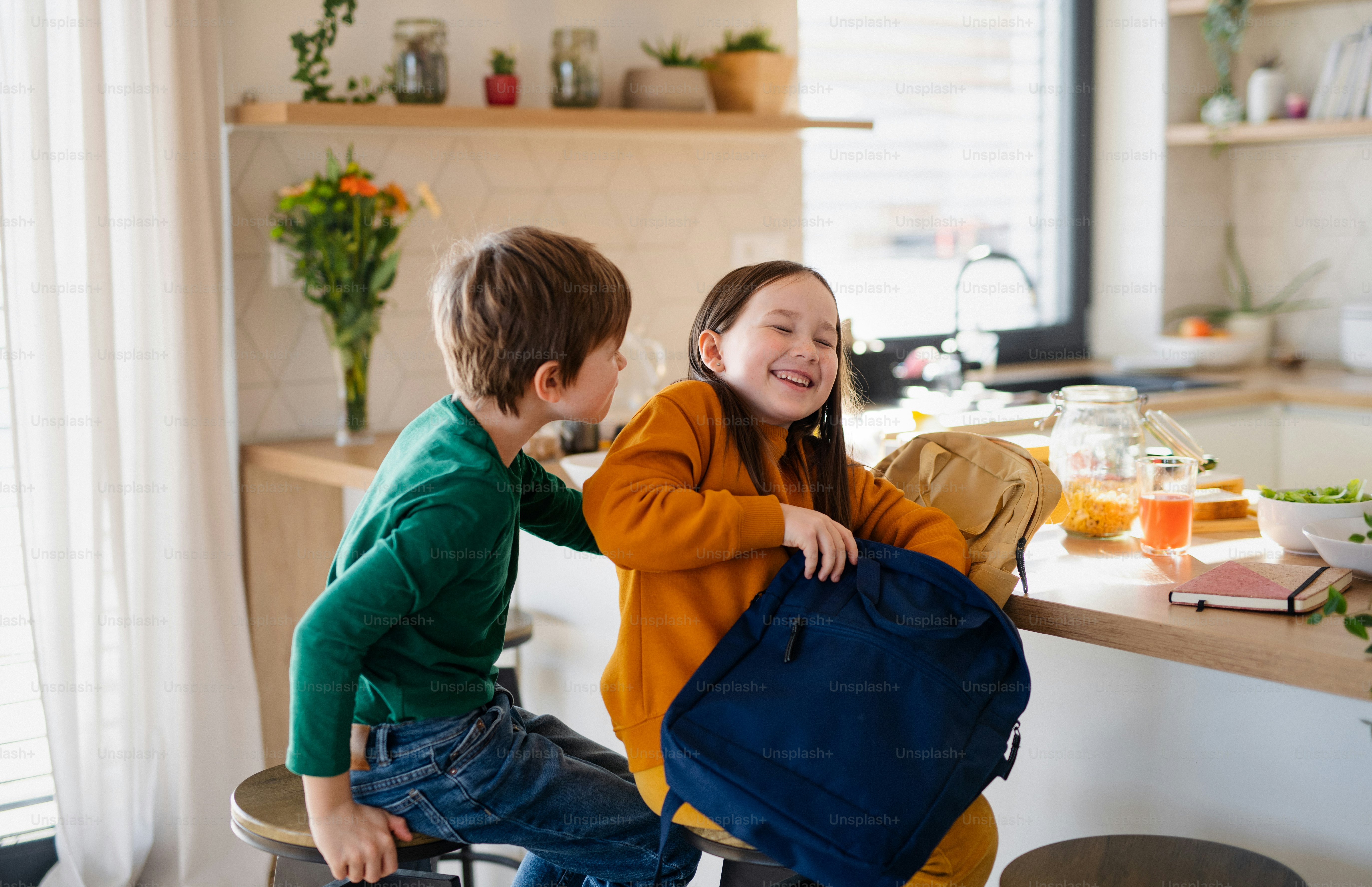 Ein kleines Mädchen, das zu Hause in der Küche eine Lunchbox für den Rucksack packt.