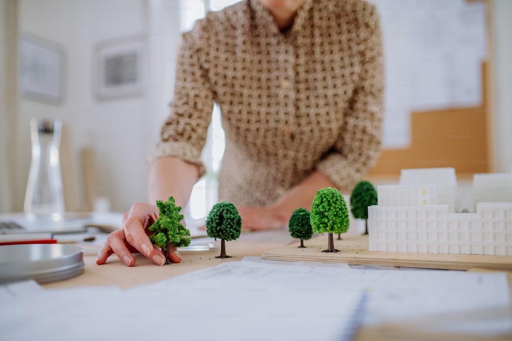 Un primer plano de la mujer arquitecta con el modelo de las casas en la oficina