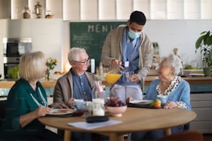 A group of cheerful seniors enjoying breakfast in nursing home care center.