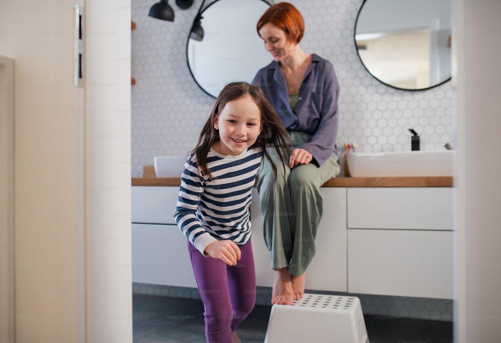 A mother with her little daughter in bathroom at home.