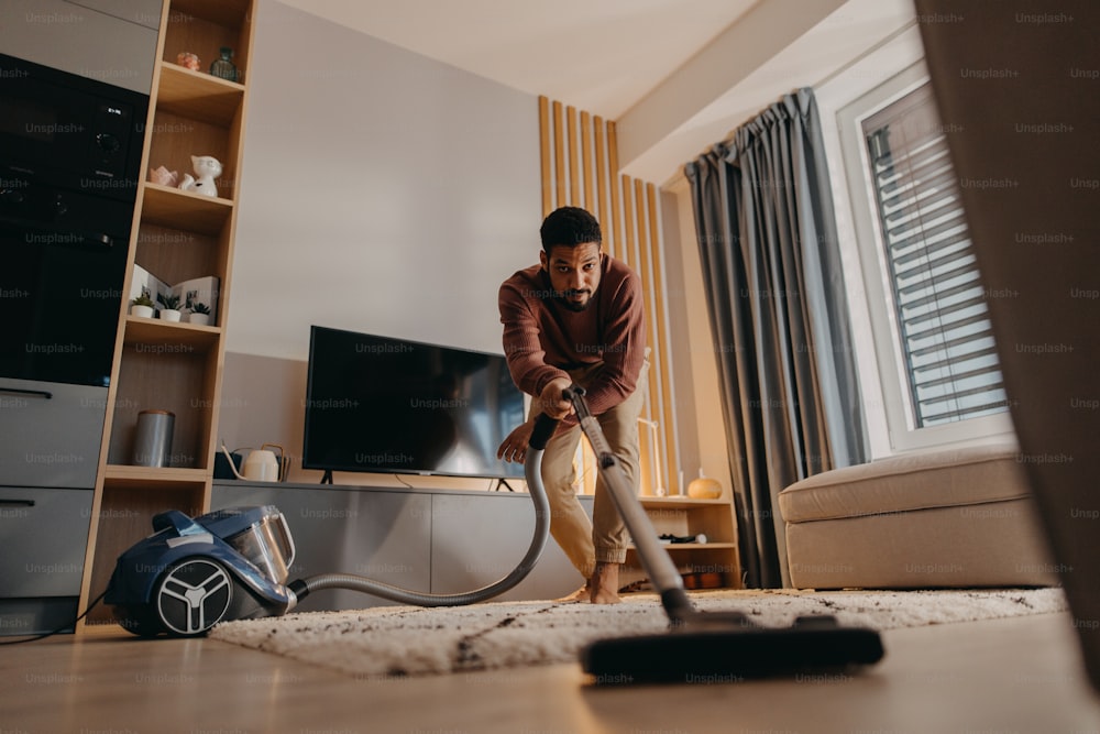 Un giovane che aspira il tappeto con l'aspirapolvere in soggiorno foto –  Apparecchio Immagine su Unsplash