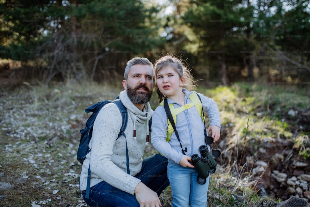 A father with small daughter with binoculars on walk in spring nature together.