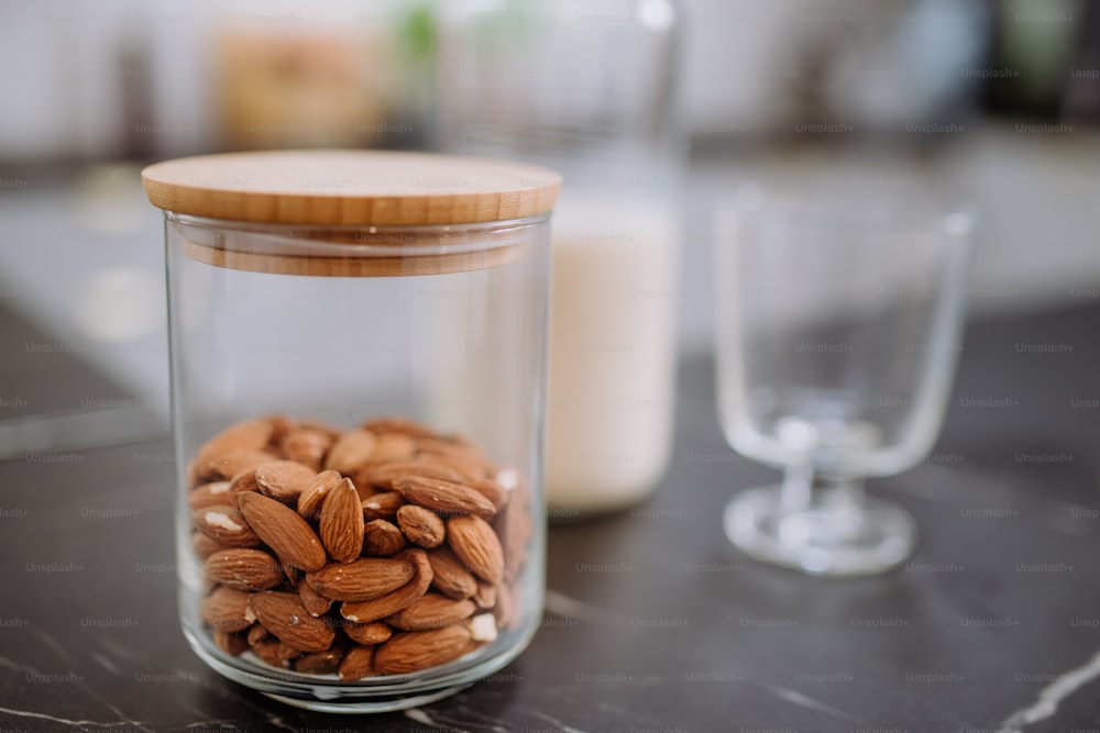 Almonds and almond milk and a glass on kitchen counter. Healthy vegan product concept.