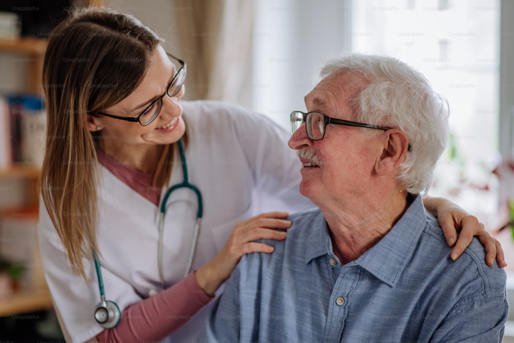 A healthcare worker or caregiver visiting senior man indoors at home.