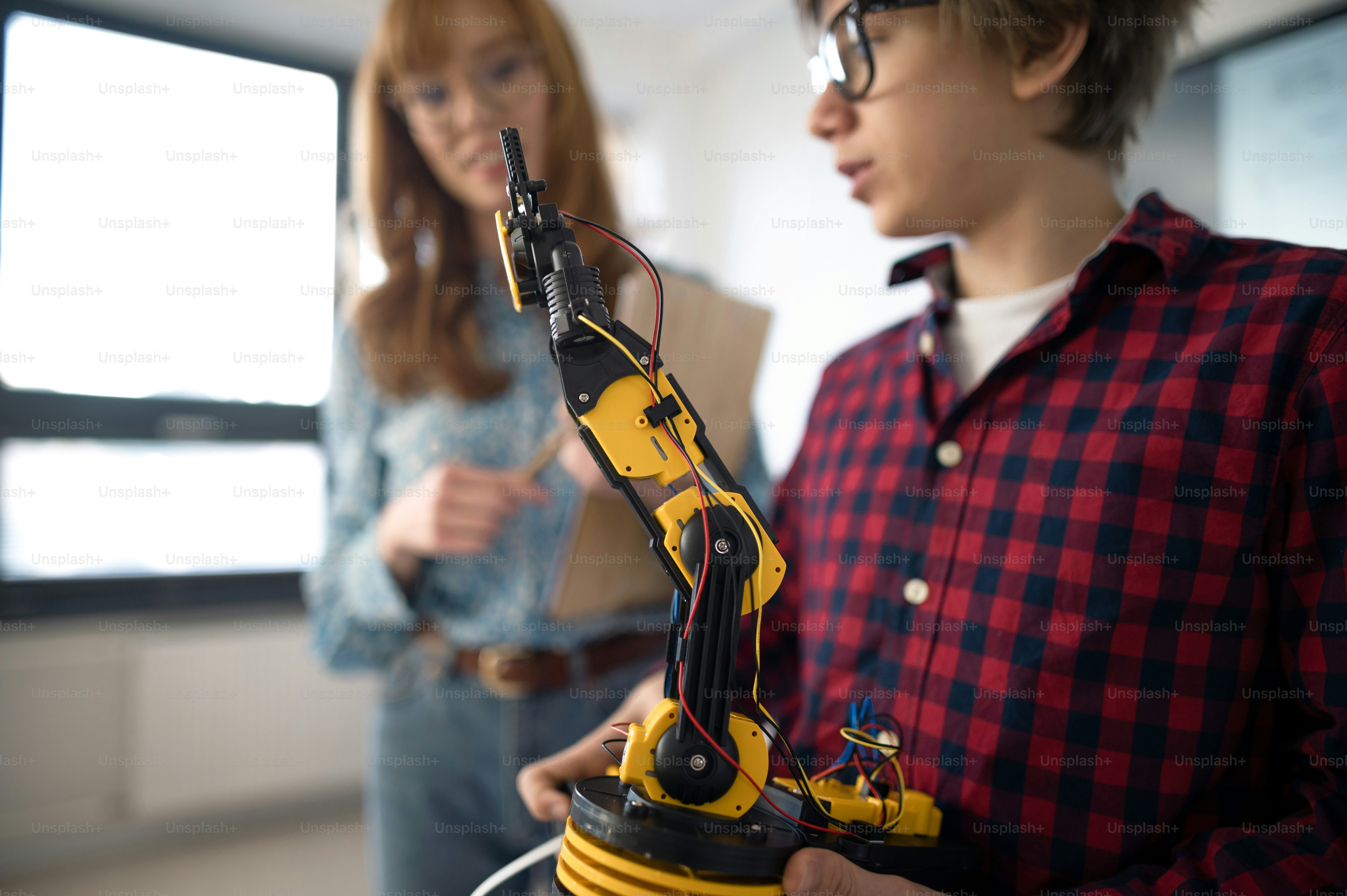 A college student presenting his builded robotic toy to young science ...