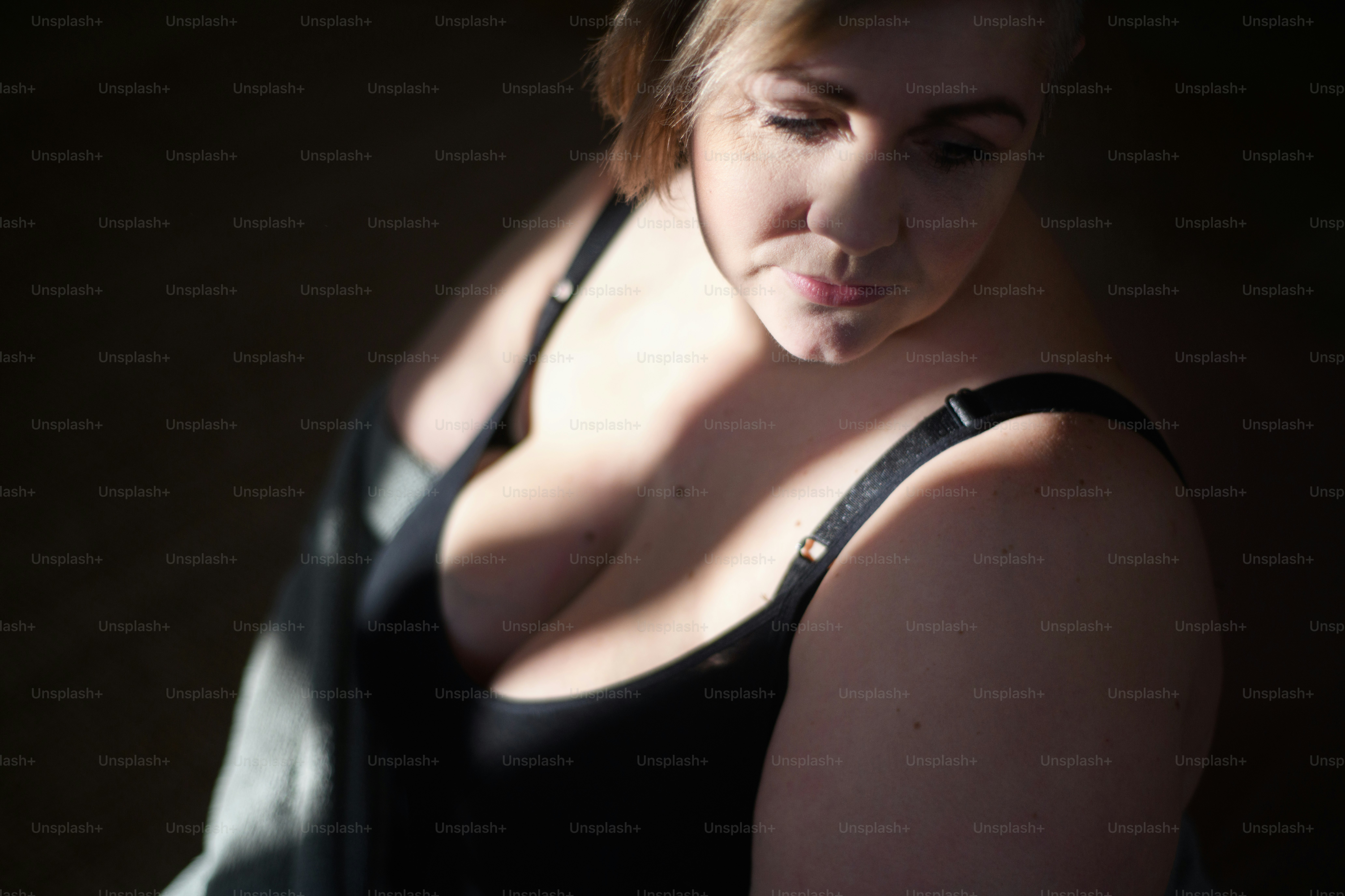 A depressed lonely  woman in underwear looking down and thinking at home.