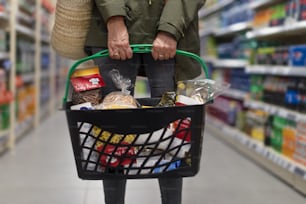 Femme faisant ses courses au supermarché, elle porte un panier plein