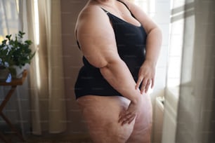 A midsection woman in underwear sitting.