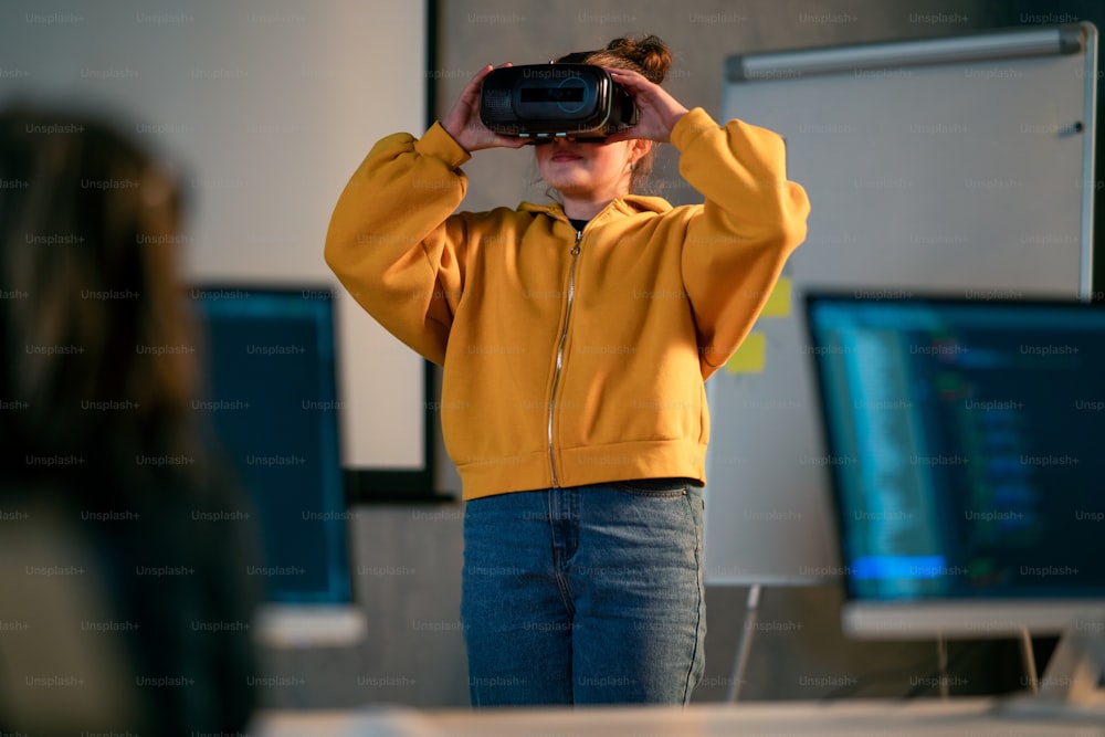 A schoolgirl wearing virtual reality goggles at school in computer science class