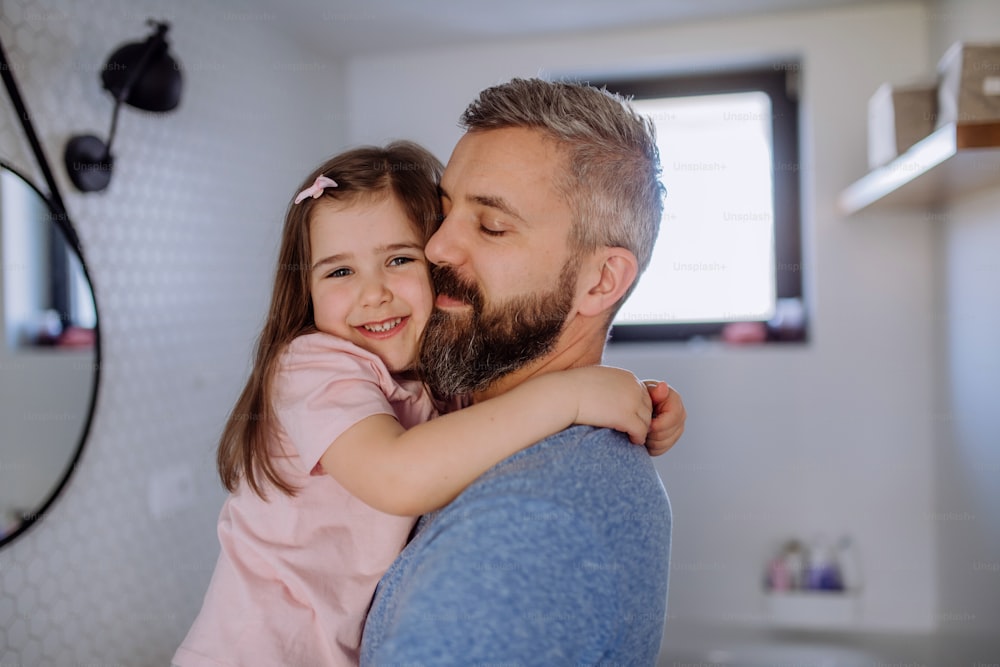 A happy father hugging his little daughter in bathroom.