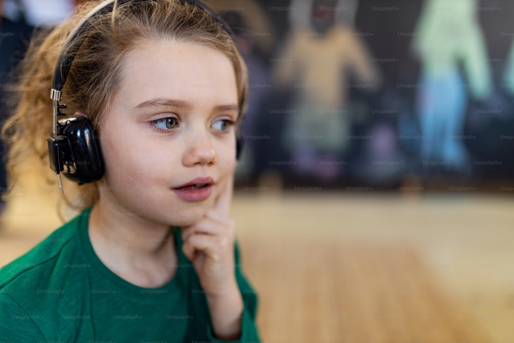 A little girl with headphones and microphone listening music, having fun and playing at home.
