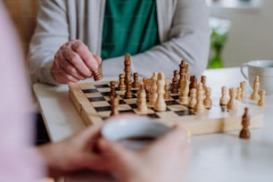 A close-up of senior man playing chess with his daughter at home.