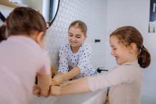 Three little sisters washing hands in a bathroom, morning routine concept.