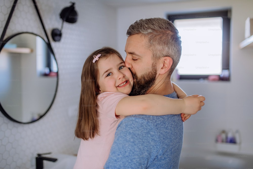 Ein Vater küsst seine kleine Tochter im Badezimmer.