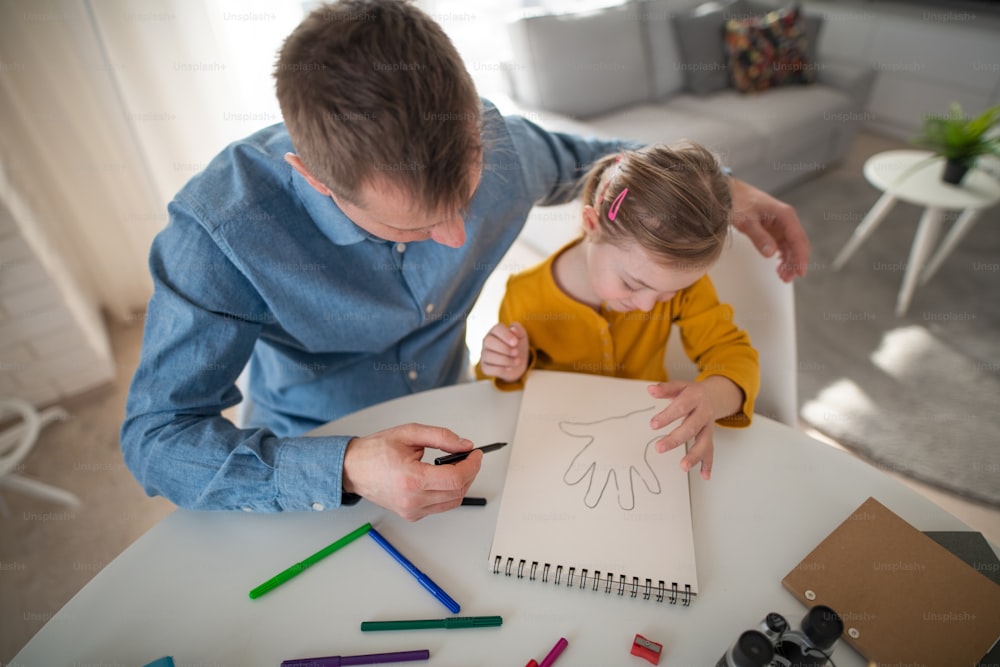 Un padre con su pequeña hija con síndrome de Down aprendiendo en casa.