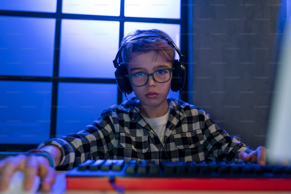 Un joven jugador con auriculares jugando a un videojuego de computadora.