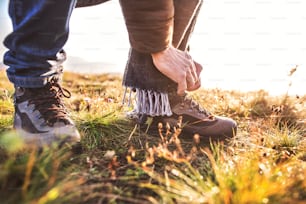 Active senior man on a walk in a beautiful autumn nature. Unrecognizable man tying his shoelaces. Close up.