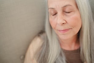 A close up of senior woman with her eyes closed.