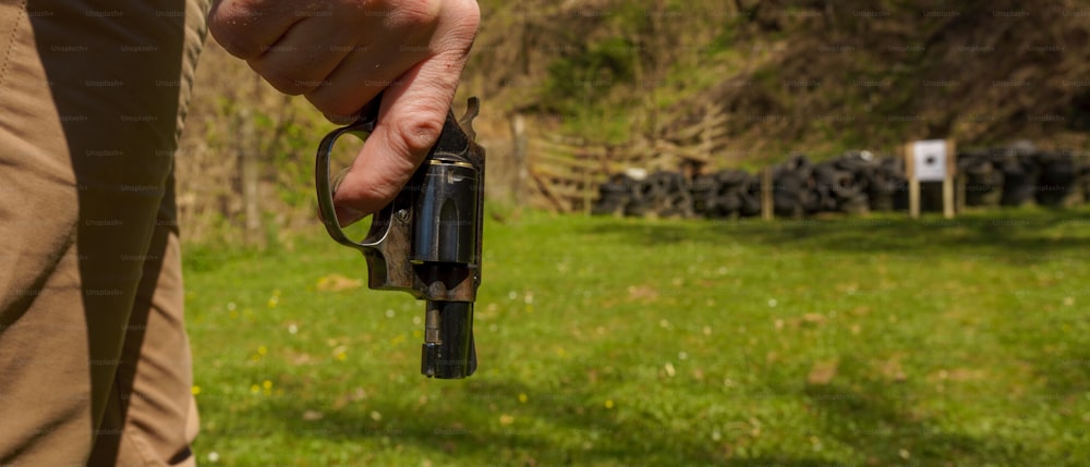 Um homem irreconhecível com revólver se preparando para atirar alvo em campo de tiro ao ar livre.