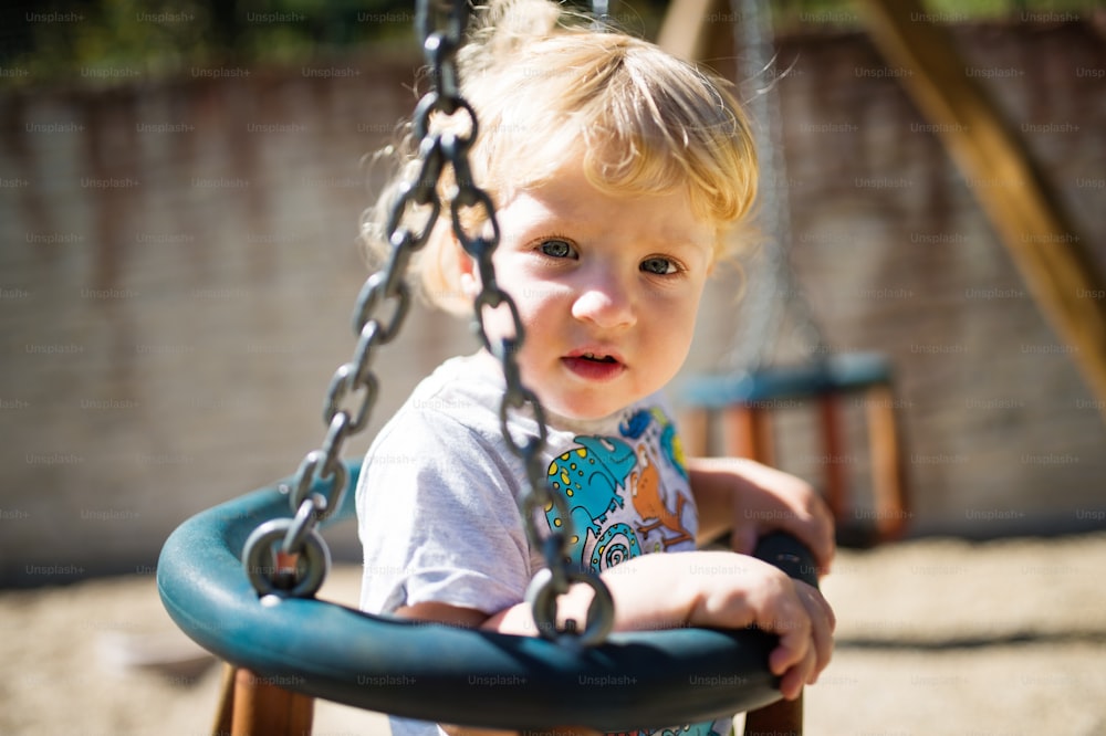 Cute little boy on the swing at the playground.
