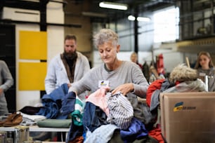 Volontari che selezionano i vestiti donati per le esigenze dei migranti ucraini, concetto di aiuto umanitario.