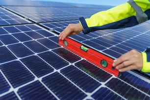 Gros plan d’une ingénieure mesurant des panneaux solaires photovoltaïques sur le toit, concept d’énergie alternative.
