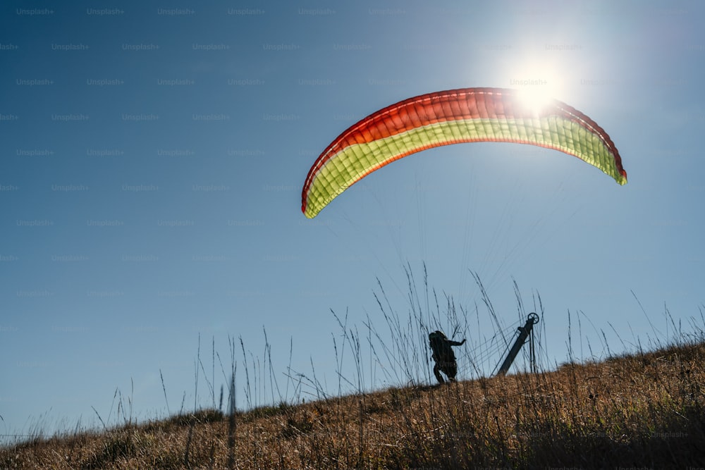 A paraglider landing on the ground against the blue sky.