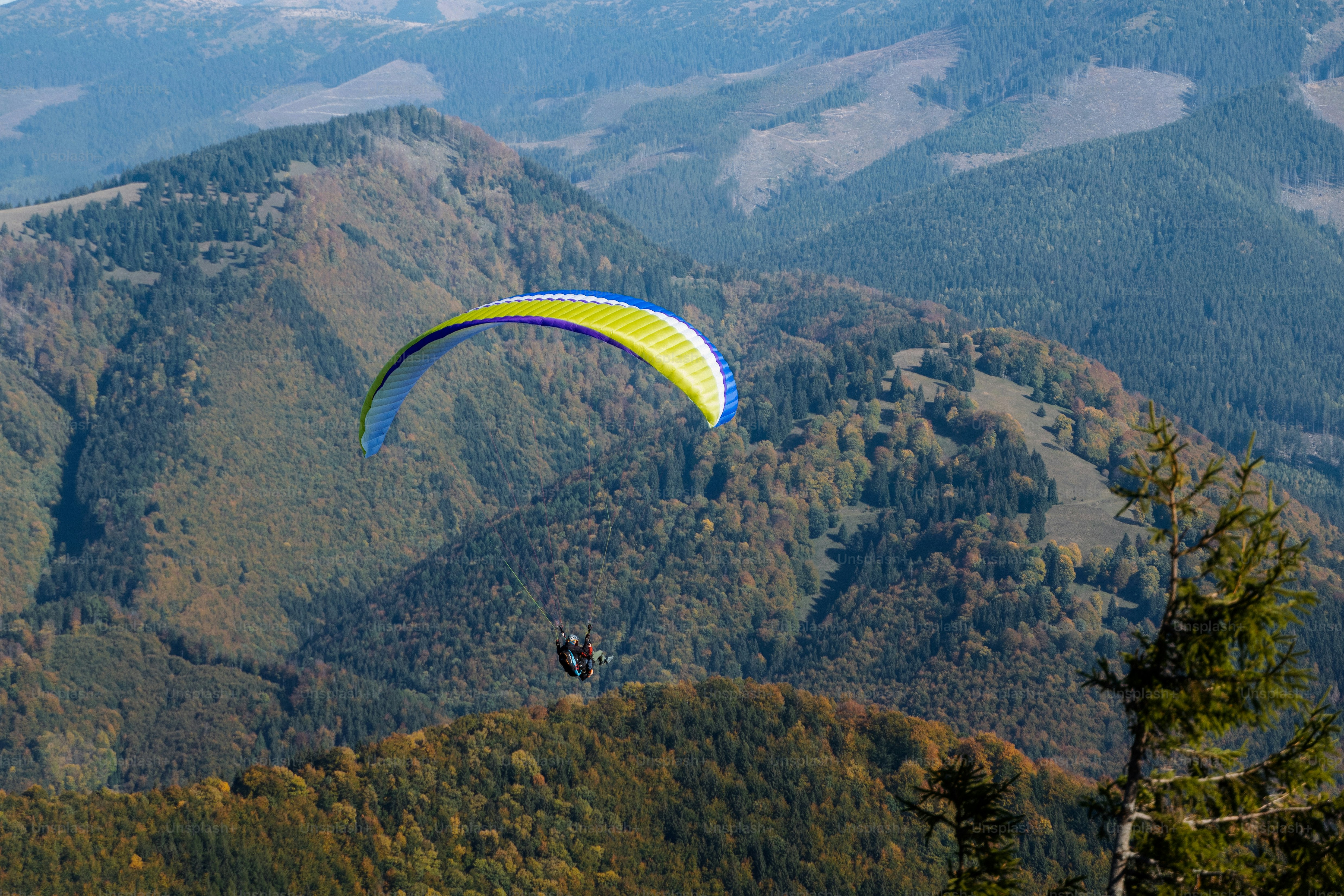 Ein Gleitschirm fliegt am blauen Himmel mit dem Berg im Hintergrund.