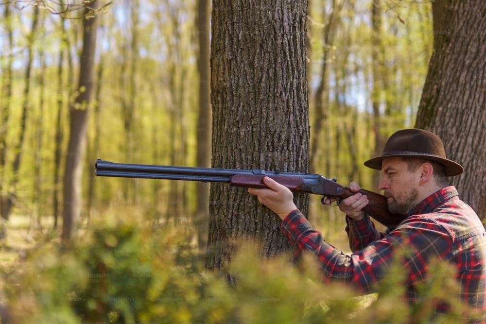 Ein Jäger zielt mit Gewehrgewehr auf Beute im Wald.
