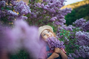 A portrait of a cheerful little girl in nature blooming lilac-purple meadow.