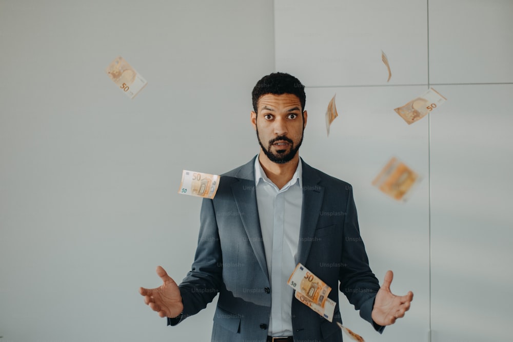 Un joven hombre de negocios serio que está en el cargo tirando el dinero, concepto de inflación.