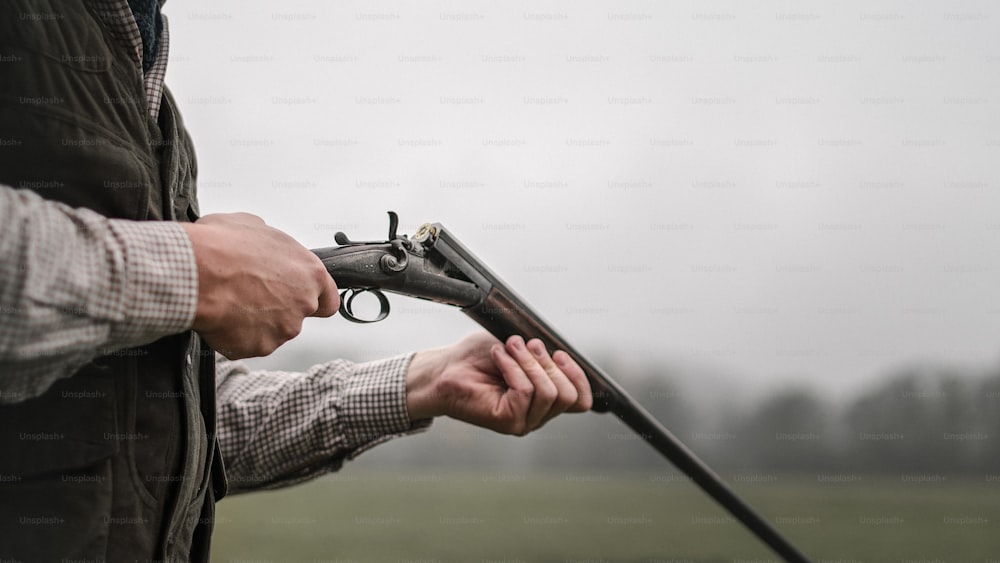 Um close-up do homem caçador carrega o cartucho em uma arma de fuzil na floresta.