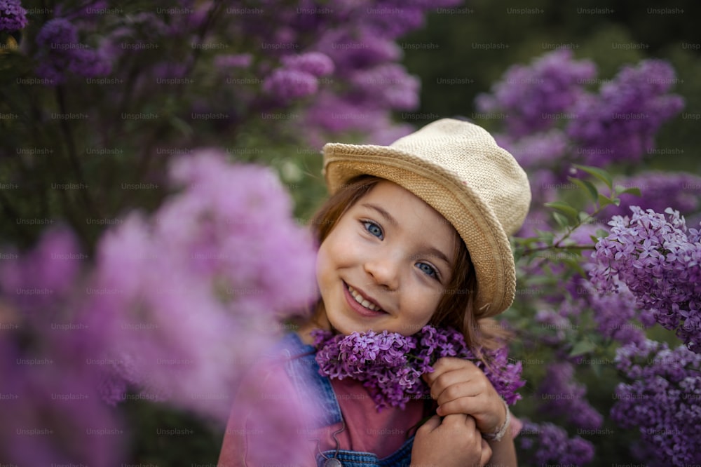 Um retrato de uma garotinha alegre na natureza florescendo prado lilás-púrpura.