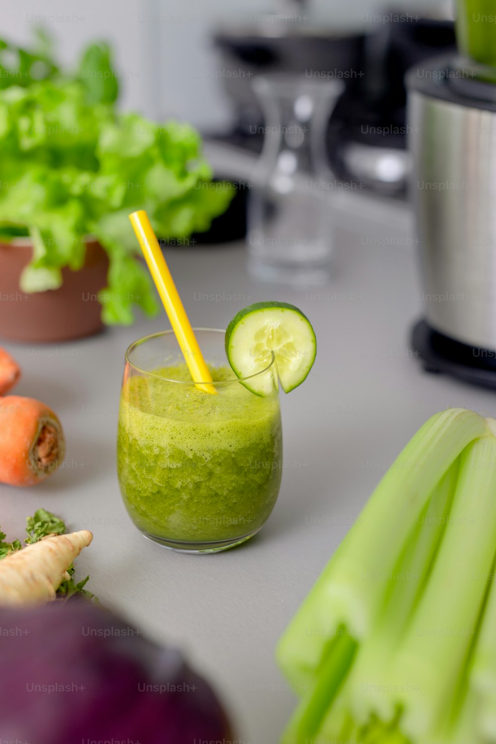 A green smoothie in glass with straw and cucumber and vegetagbles at background, detox, vegan, vegetarian healthy vegetable drink
