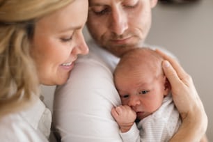 Eine lächelnde Mutter und ein Vater halten ihre neugeborene Tochter zu Hause
