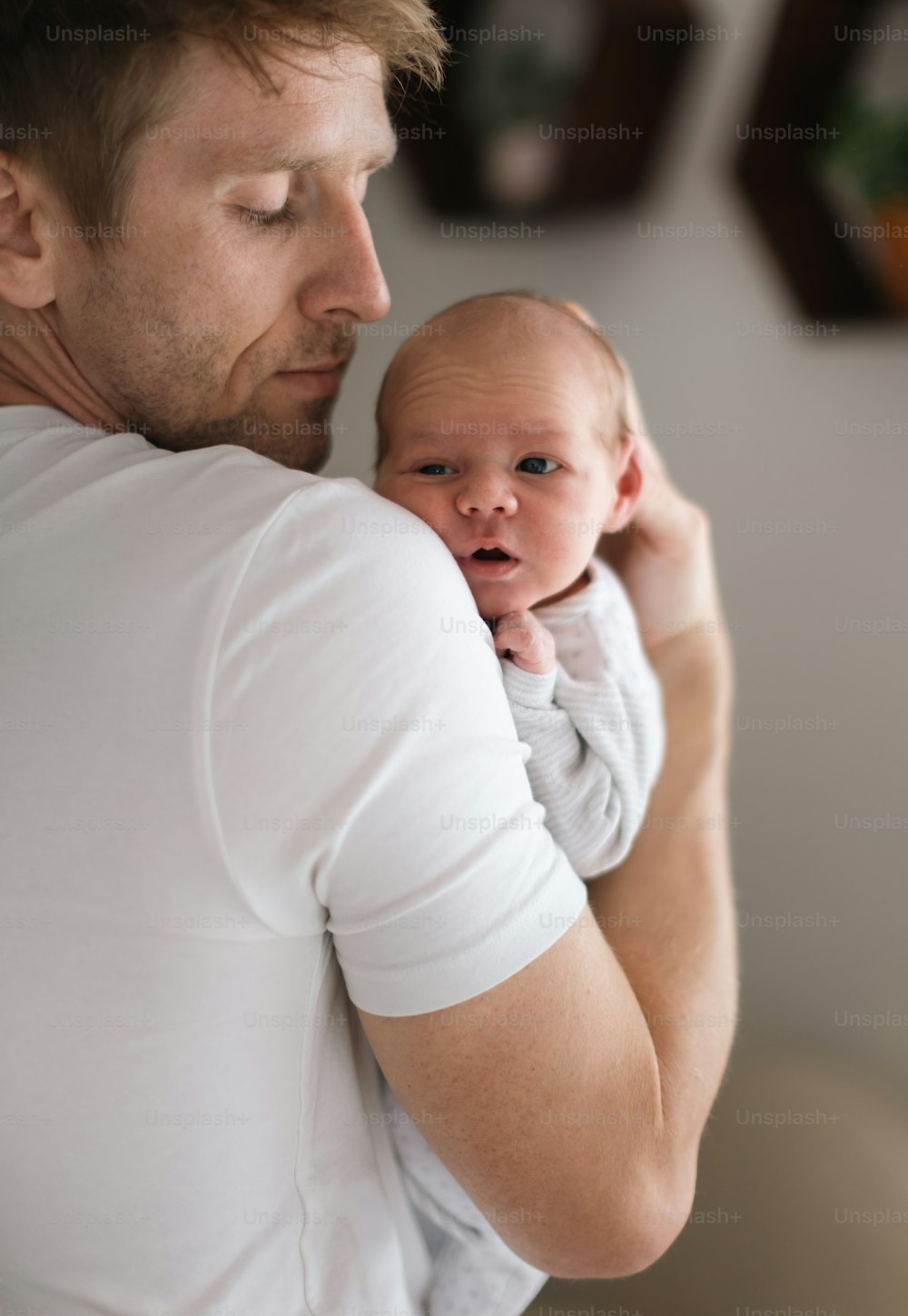 A father holding his newborn son at home.