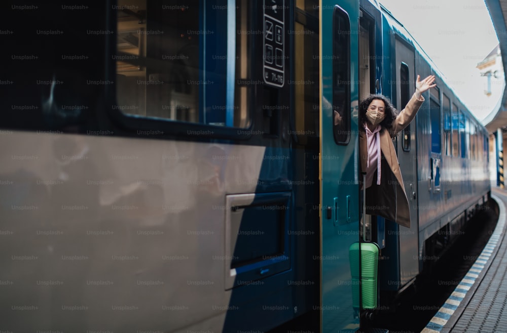駅のプラットホームで電車を降りる荷物を持った幸せな若い旅行者の女性