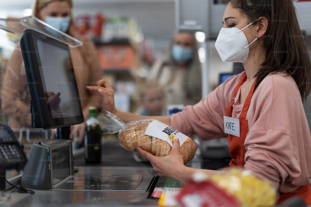 A checkout counter hands of the cashier scans groceries in supermarket.