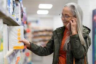 Donna anziana che sceglie e acquista prodotti da farmacia al supermercato.