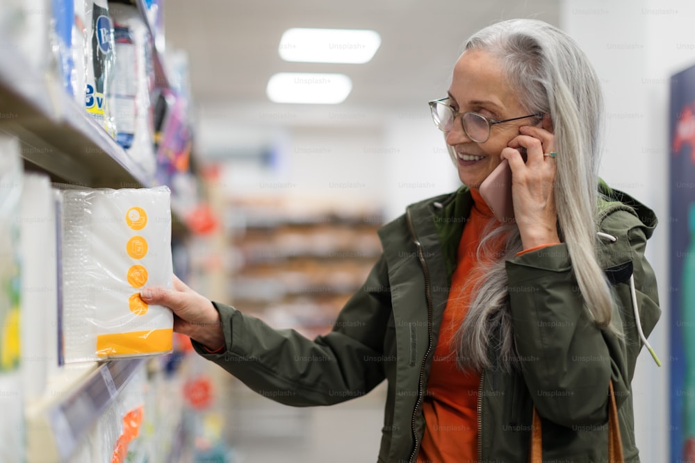 Femme âgée choisissant et achetant des produits de pharmacie dans un supermarché.