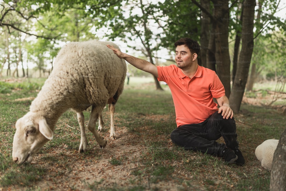 Happy young man with down syndrome caressing a sheep outdoors in park