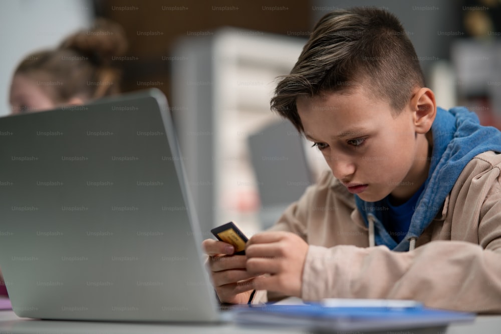 A schoolboy using computer in classroom at school