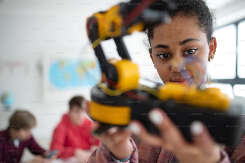 A college student holding her robotic toy at robotics classroom at school.