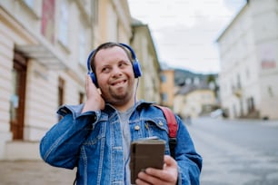 A happy young man with Down sydrome listening to music when walking in street.