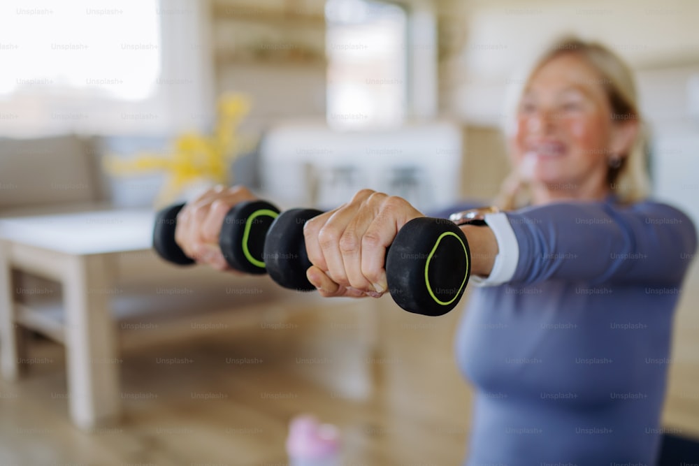 Uma mulher idosa em forma que se exercita com halteres em casa, conceito de estilo de vida ativo.
