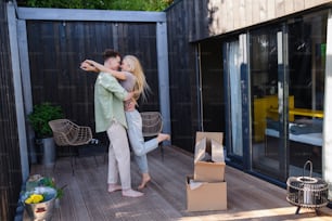 A cheerful young couple moving in their new tiny house in woods. Conception of moving and sustainable living.