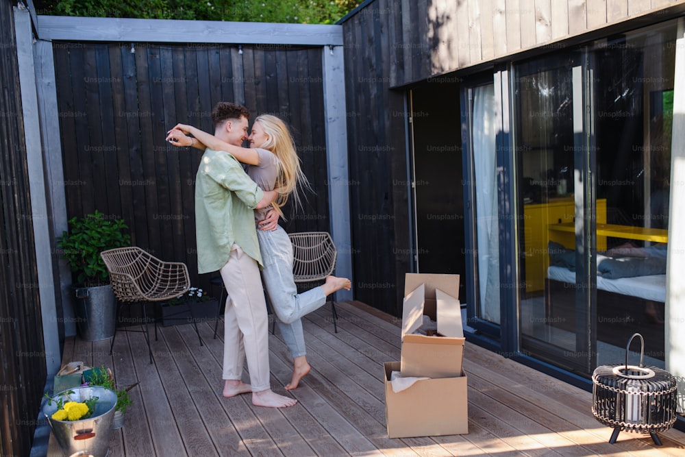Ein fröhliches junges Paar zieht in ihr neues kleines Haus im Wald. Konzeption von Bewegung und nachhaltigem Leben.