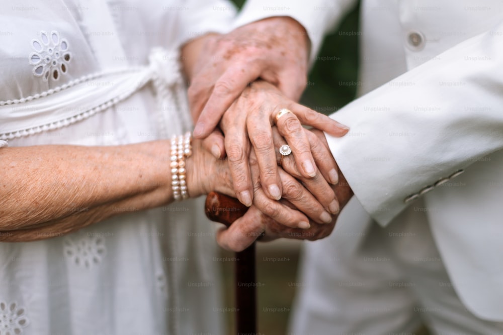 Nahaufnahme von Seniorenhänden mit goldenen Eheringen während ihrer Ehe.